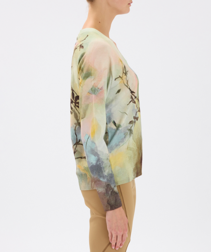 Person wearing a long-sleeve, floral-patterned top with a neutral background