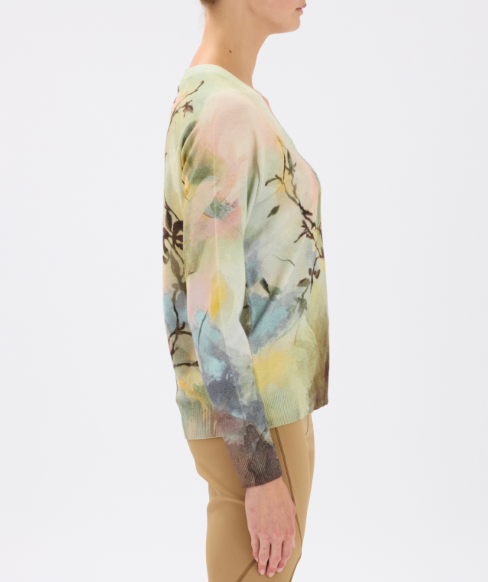 Person wearing a long-sleeve, floral-patterned top with a neutral background