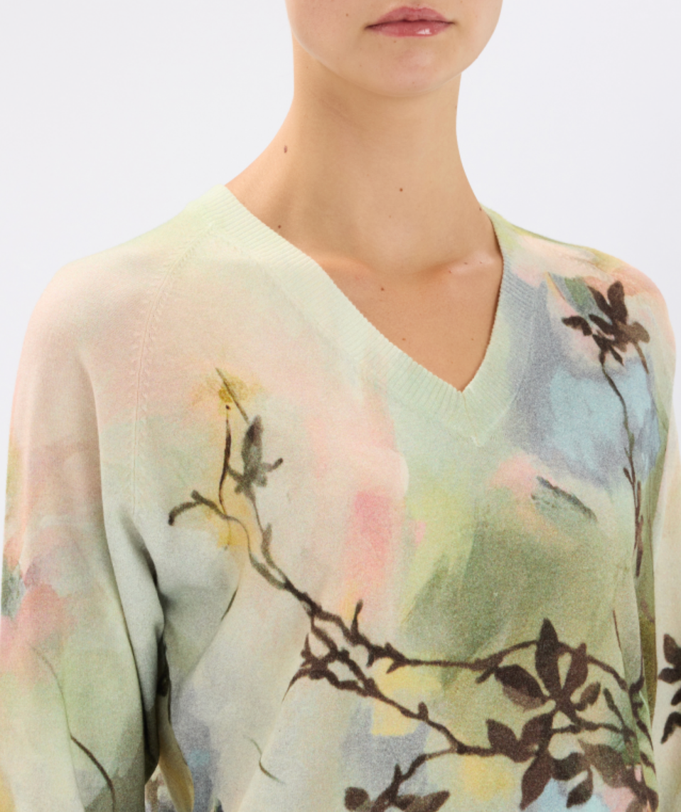Light green sweater with floral pattern worn by a person on a white background
