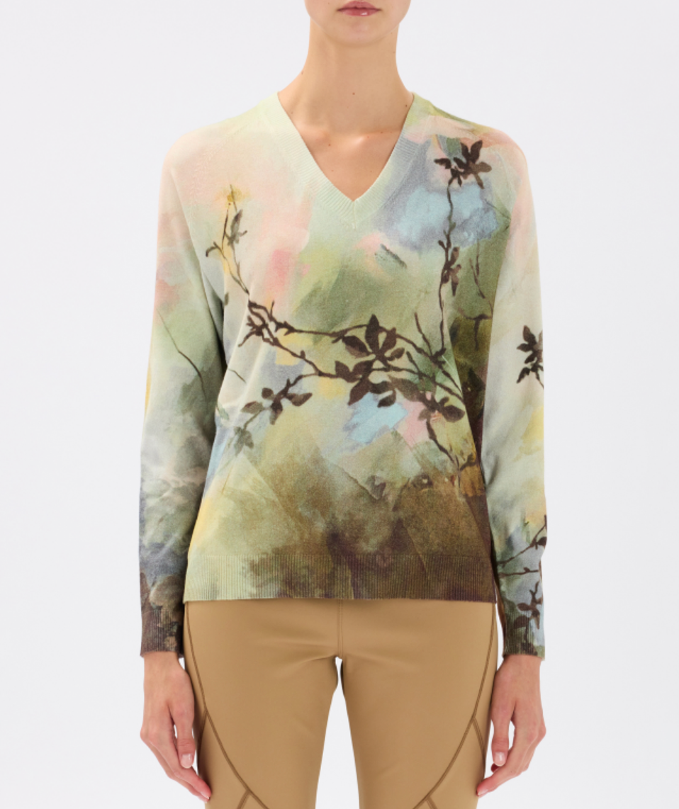 Woman wearing a long-sleeve top with a nature-themed print on a white background