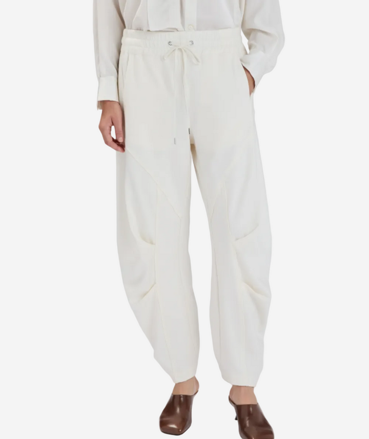 Person wearing white pants with a drawstring waist on a plain background