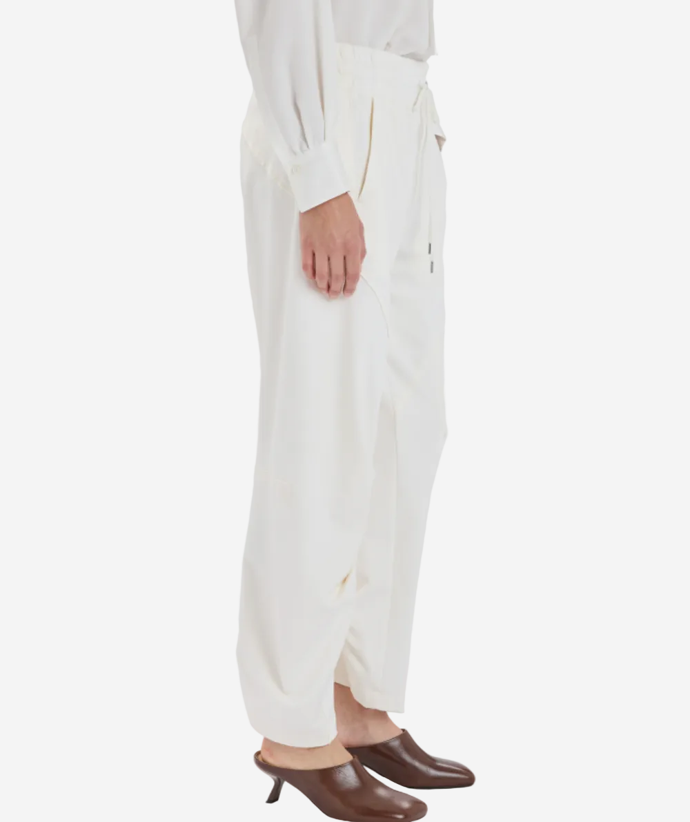 Person wearing white pants and brown shoes on a white background
