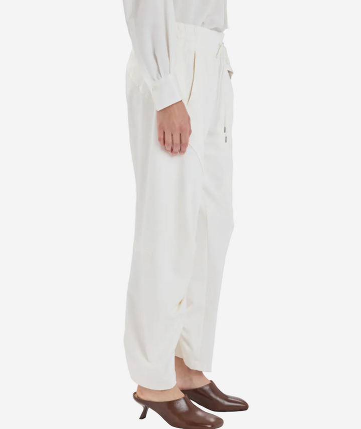 Person wearing white pants and brown shoes on a white background