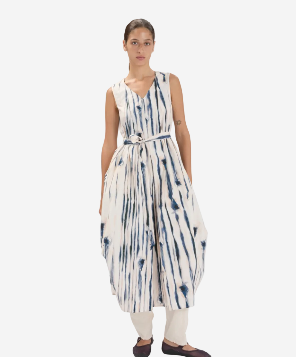 Woman wearing a sleeveless, tie-dye dress with a white background