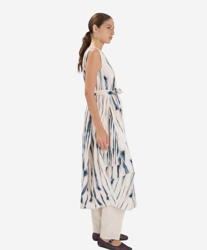 Woman wearing a sleeveless, tie-dye dress with a white background