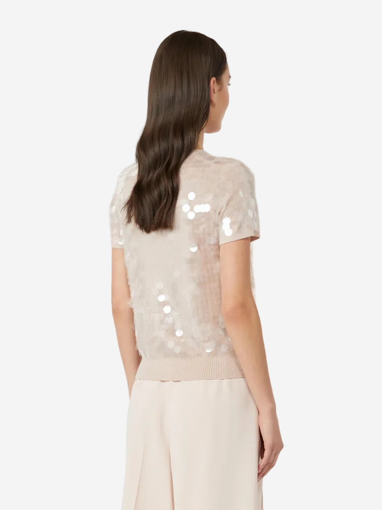 Woman wearing a beige sequin top and pants on a white background