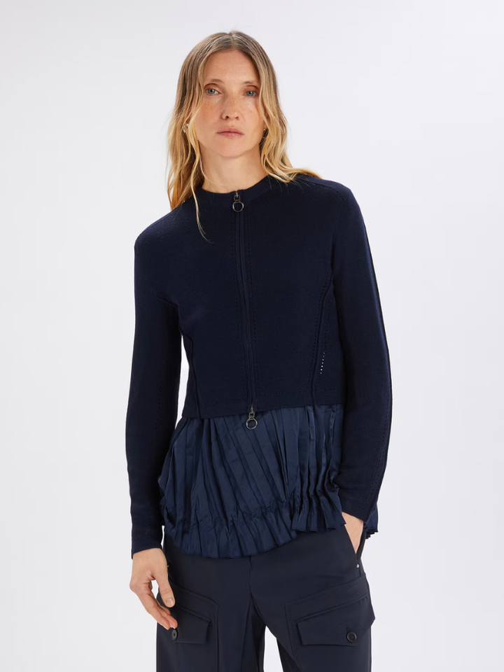 Woman wearing a navy blue long-sleeve top with a ruffled design on a white background