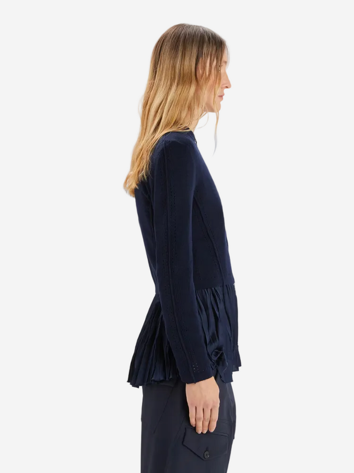 Woman wearing a navy blue blouse with ruffled sleeves on a white background