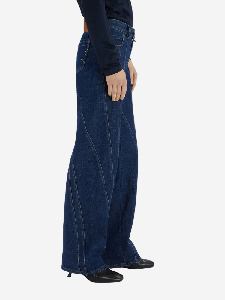 Person wearing dark blue wide-leg jeans on a white background