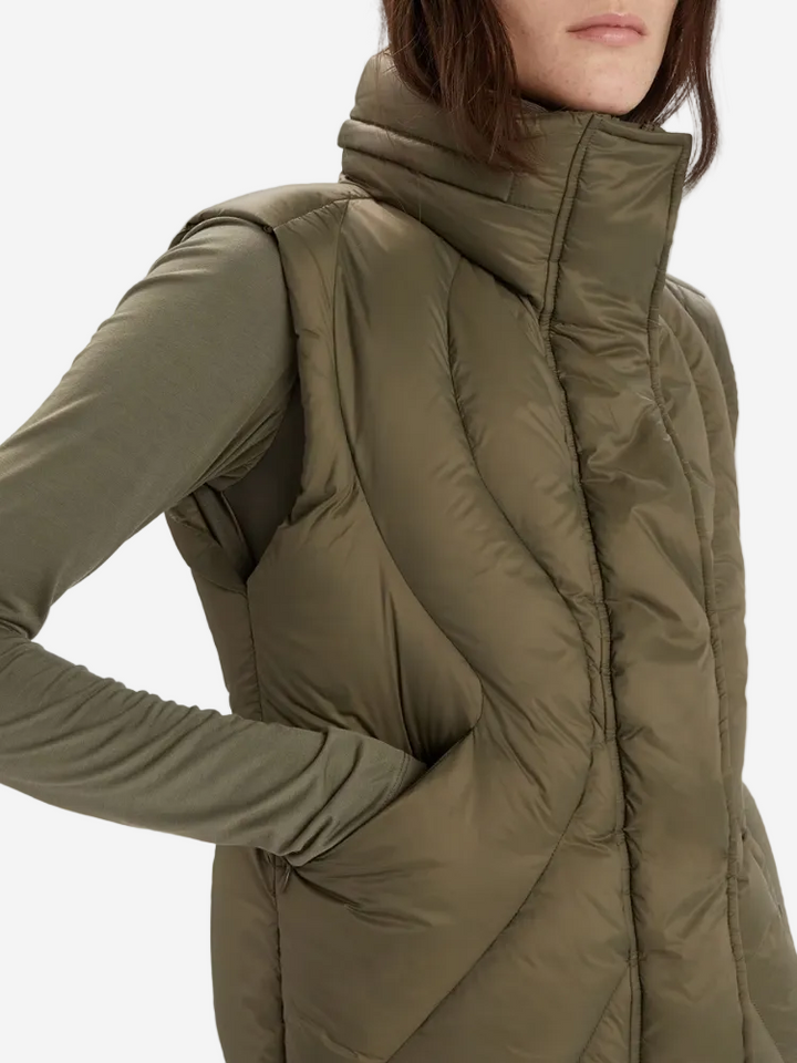 Person wearing a green puffer vest on a white background
