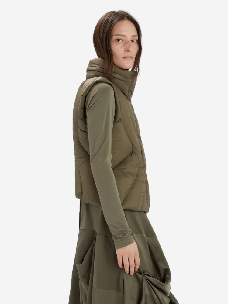 Person wearing a green outfit with a puffer vest on a white background