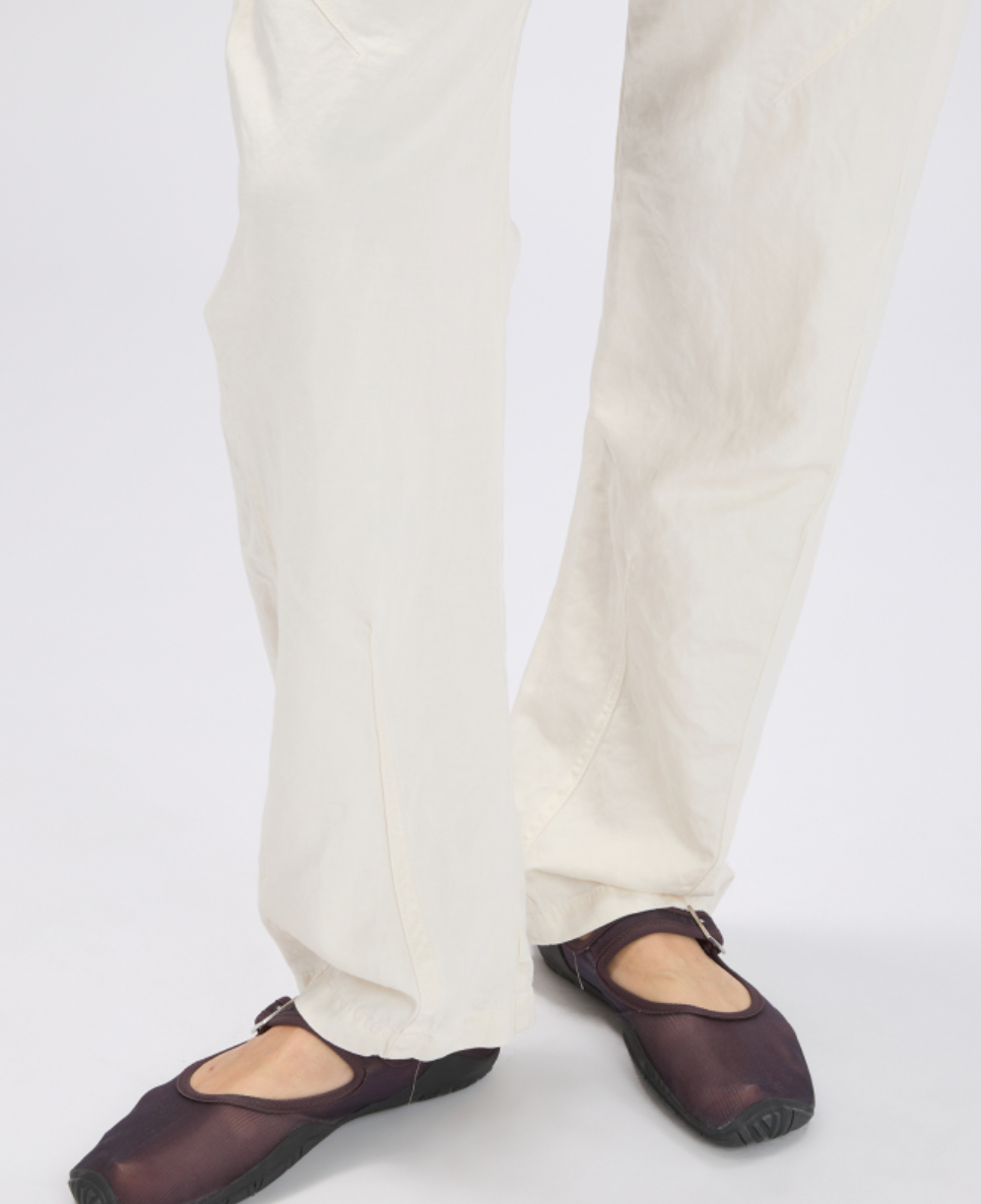 Person wearing white pants and dark brown shoes on a white background