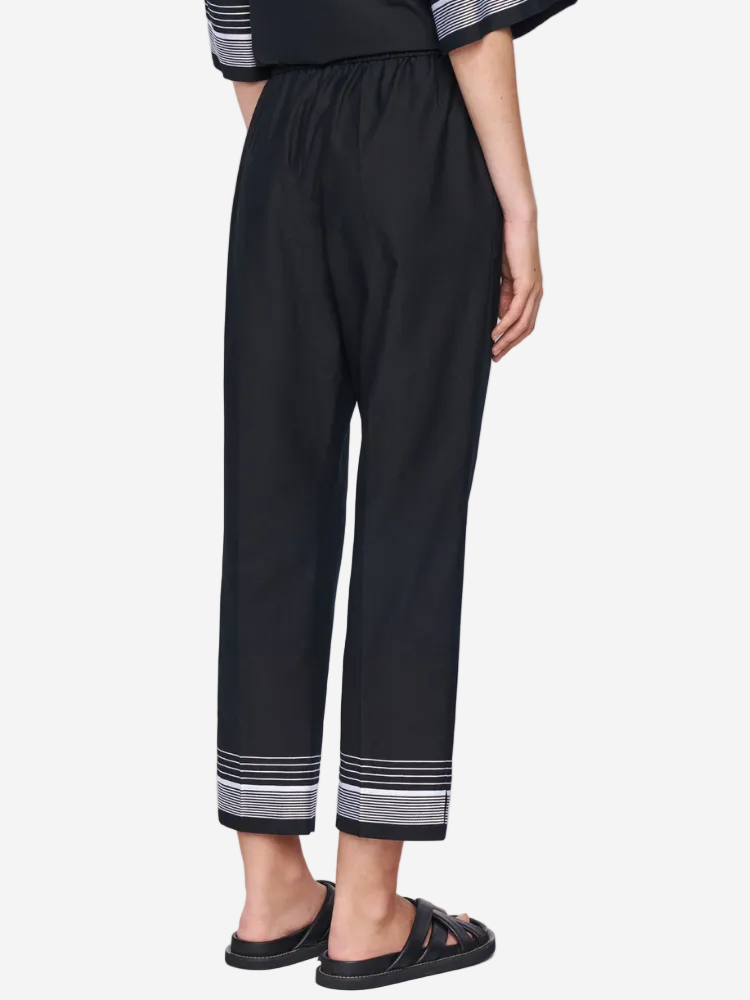 Black pants with striped cuffs worn by a person on a white background