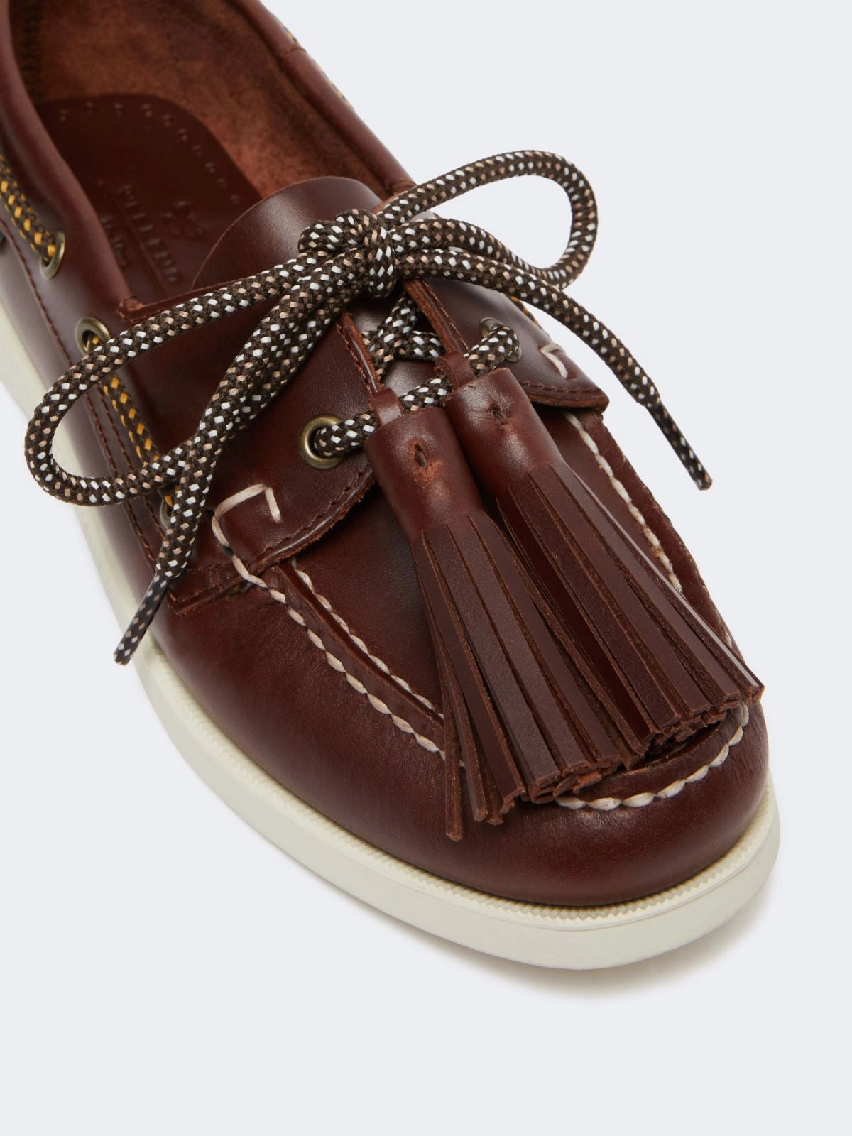 Brown leather shoe with tassels and braided laces on a white background