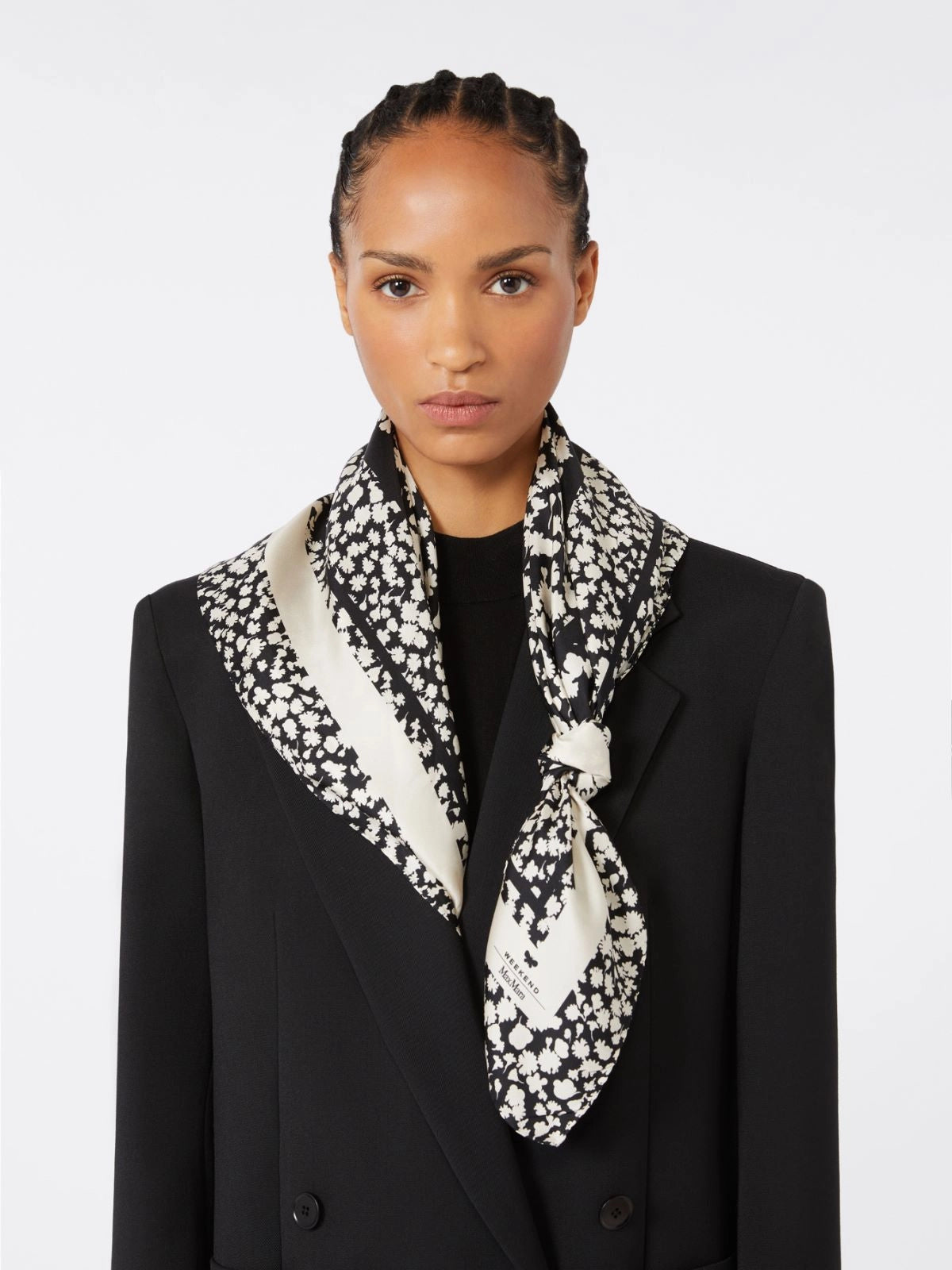 Woman wearing a black and white patterned scarf with a plain background