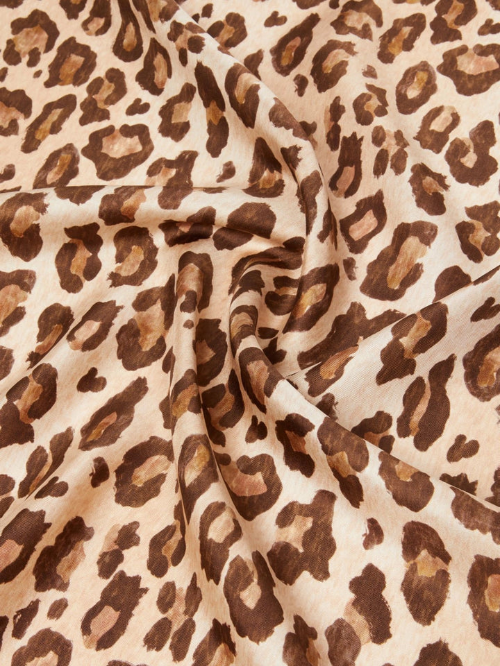 Leopard print fabric with brown and beige spots on a beige background