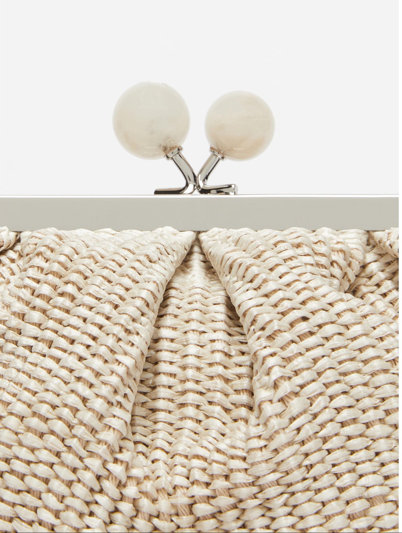 Close-up of a textured clutch bag with a metallic frame and spherical clasps.