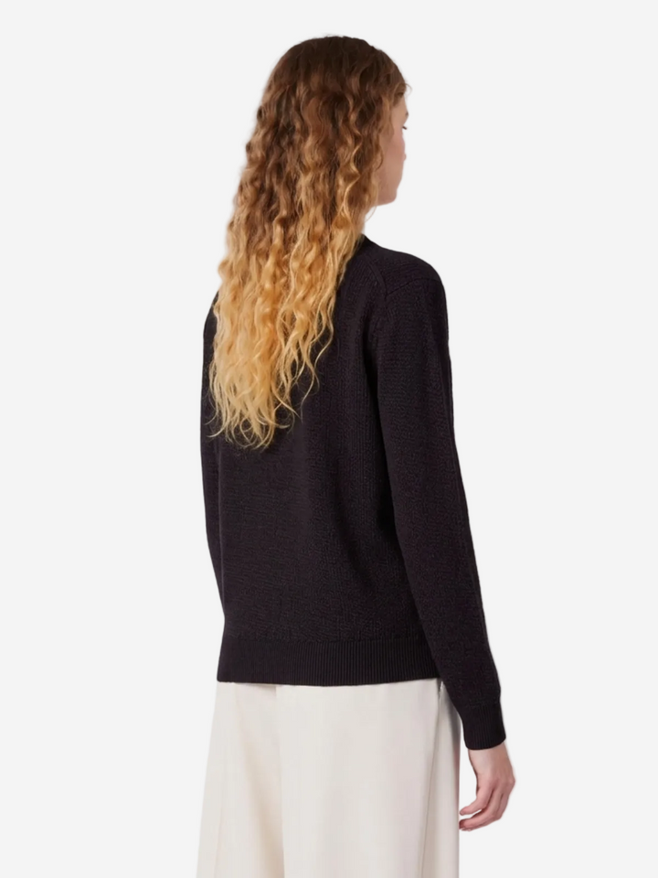 Person wearing a black sweater and white pants on a white background