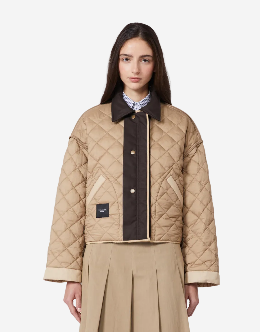Woman wearing a beige quilted jacket with a dark collar on a white background