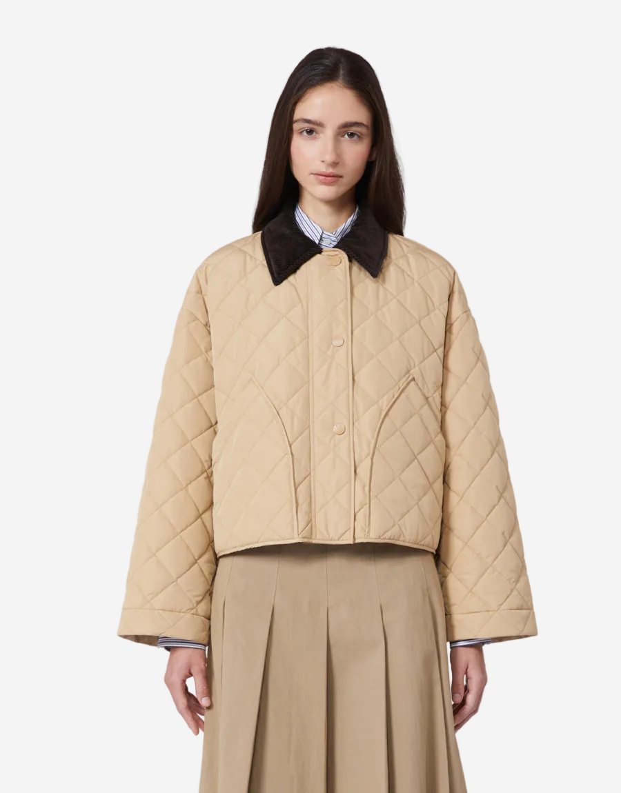 Woman wearing a beige quilted jacket with a black collar on a white background