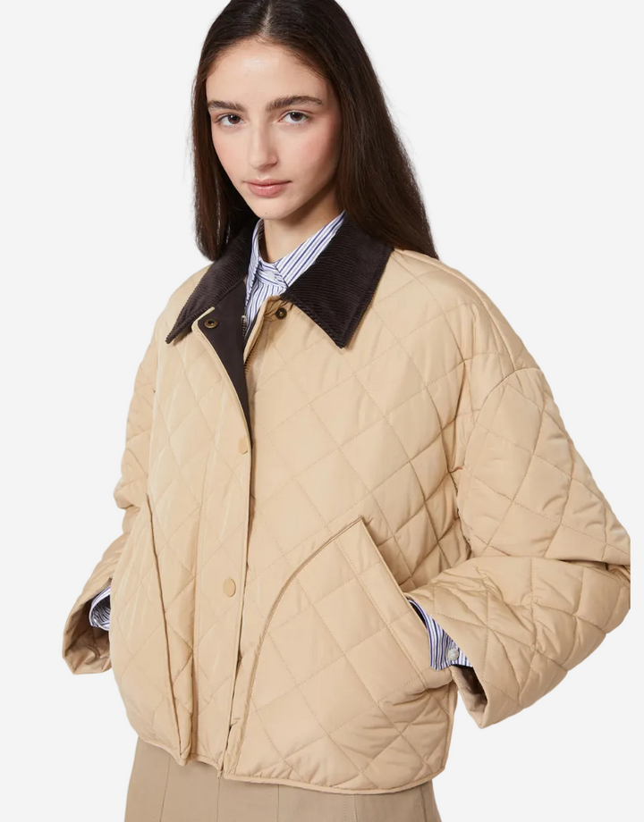 Woman wearing a beige quilted jacket with a dark collar on a white background
