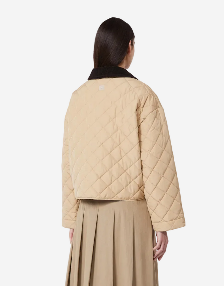 Person wearing a beige quilted jacket and skirt on a white background