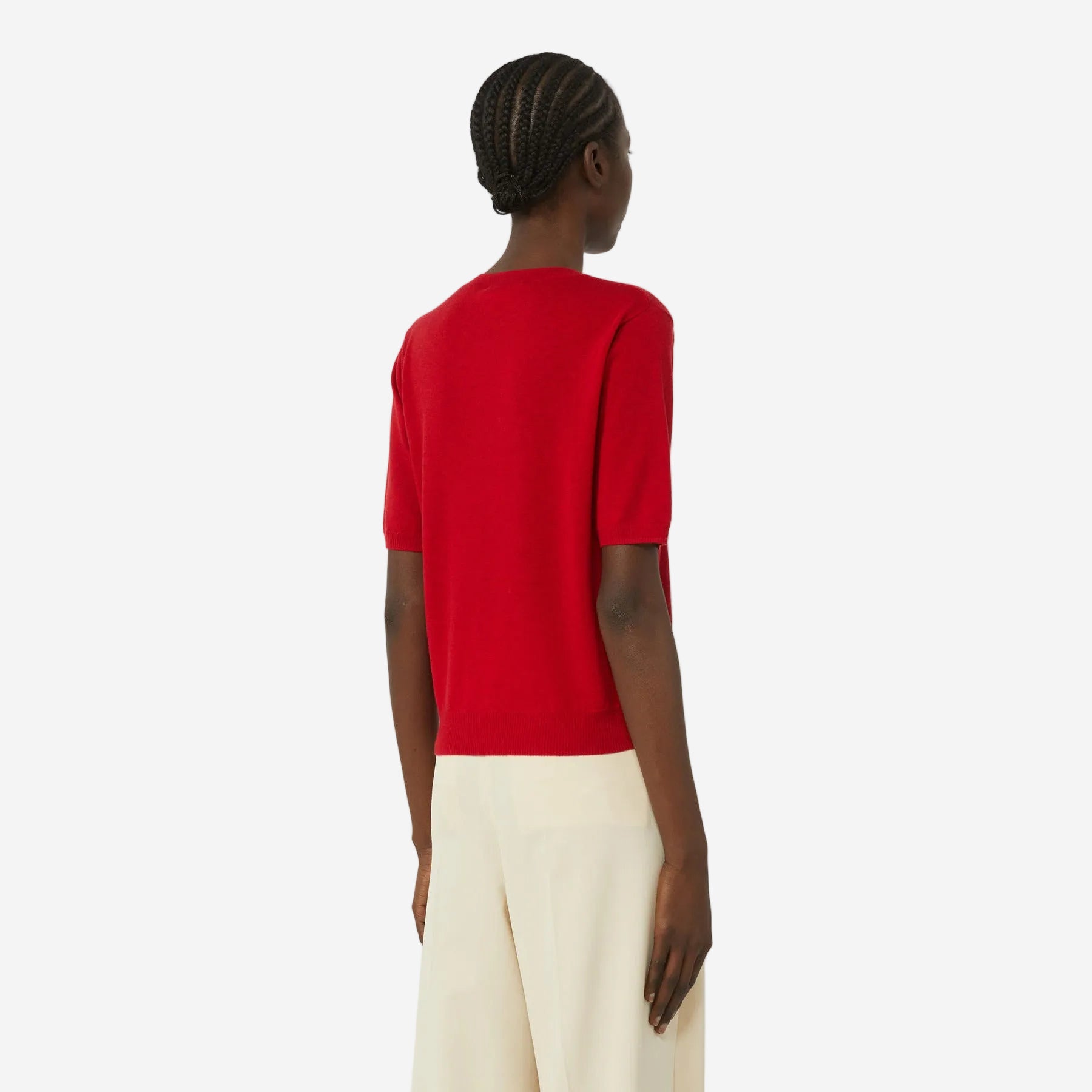 Person wearing a red shirt and white pants on a plain background