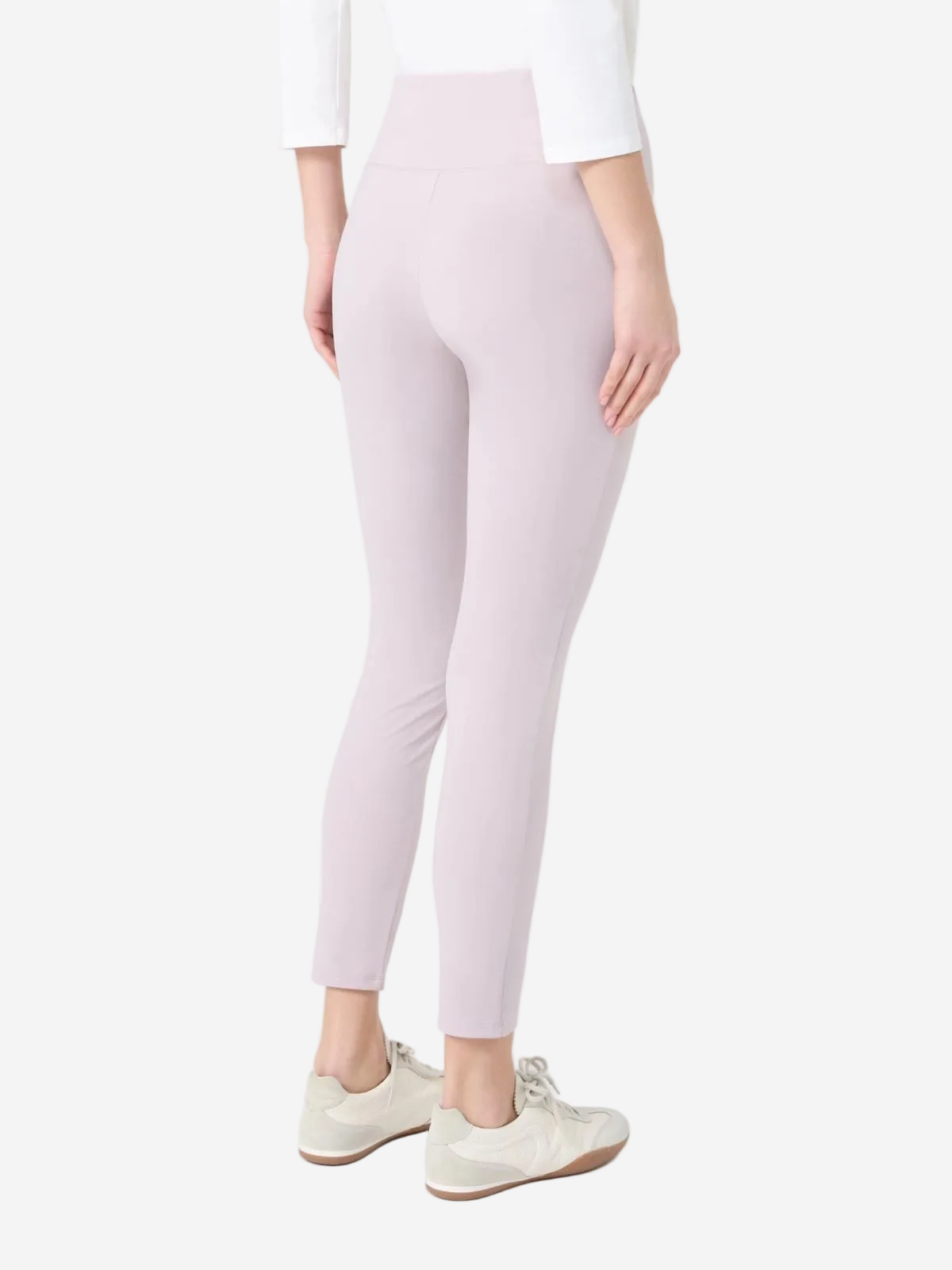 Person wearing light pink leggings and white sneakers on a white background