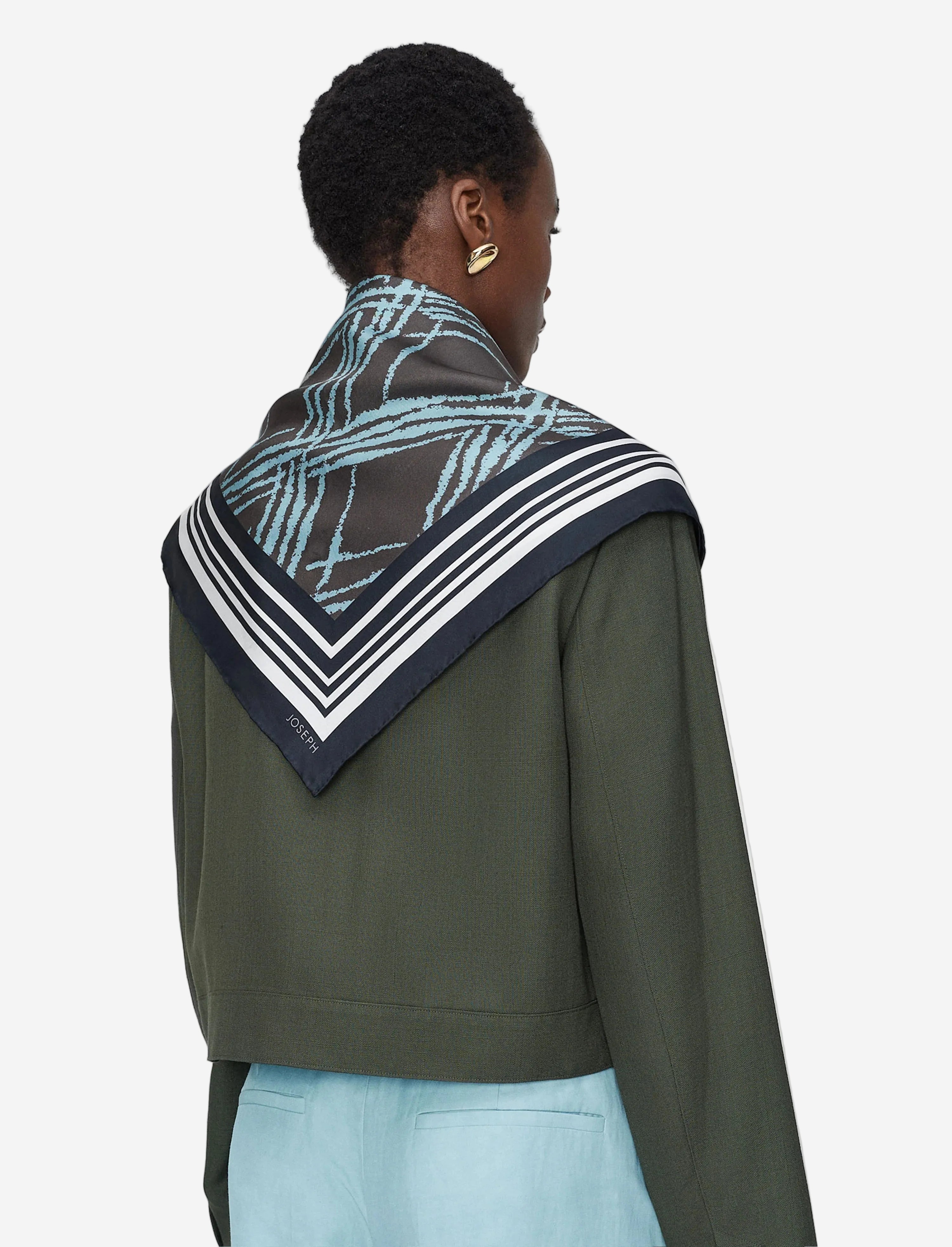 Person wearing a green jacket with a patterned hood against a light gray background