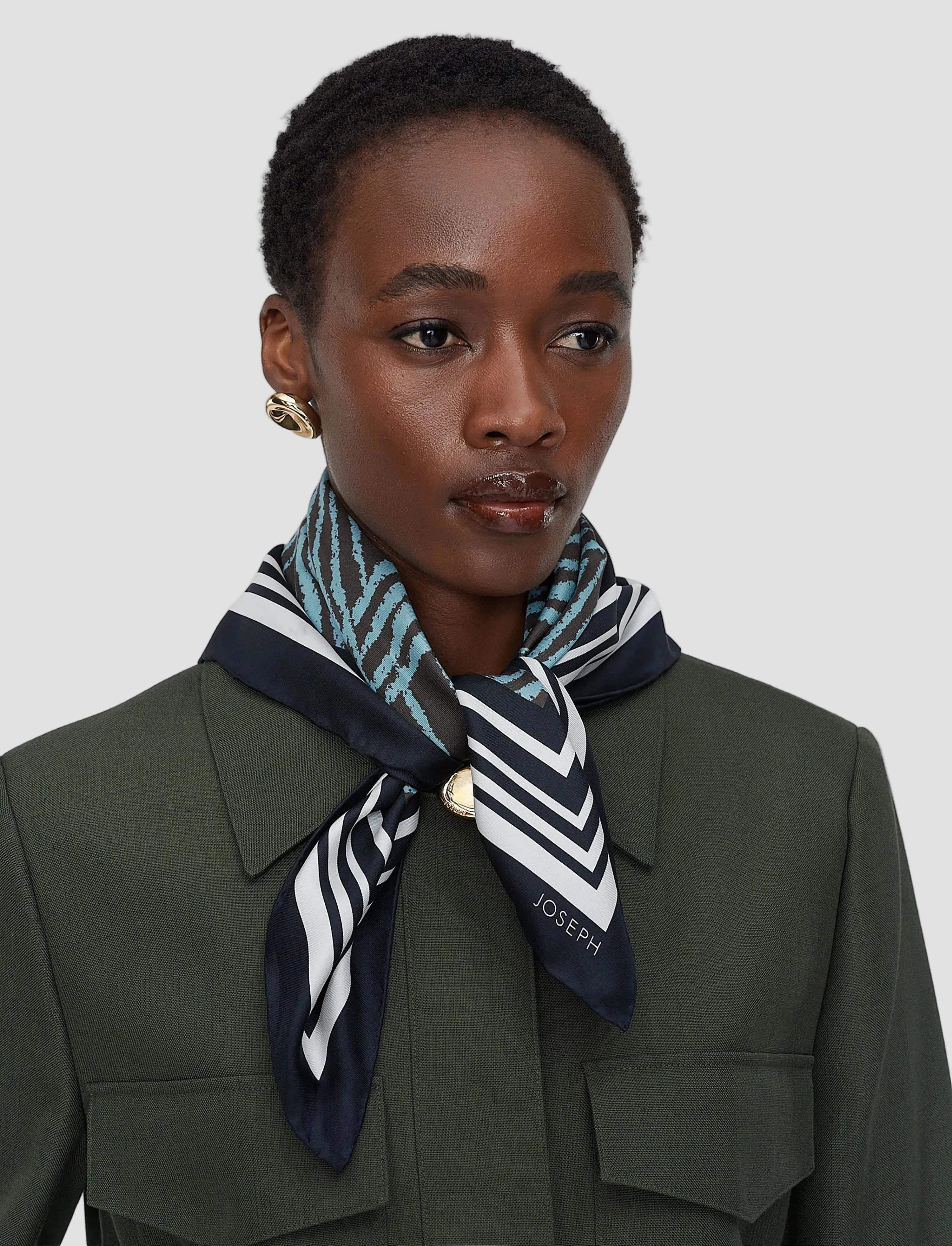 Woman wearing a patterned scarf with 'JOSEPH' branding on a plain background