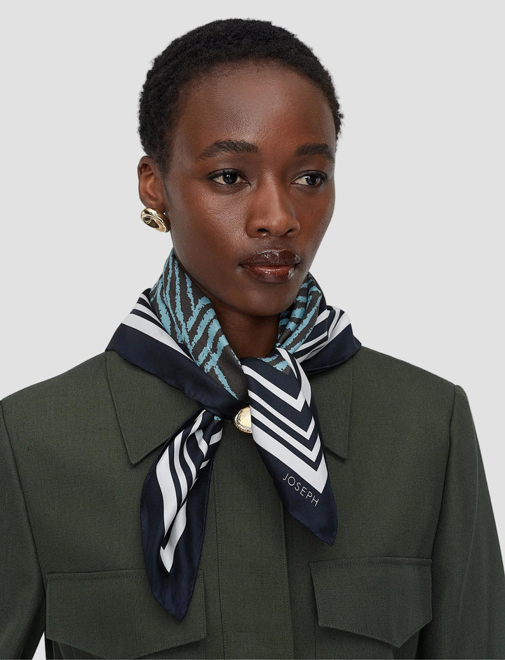 Woman wearing a patterned scarf with 'JOSEPH' branding on a plain background