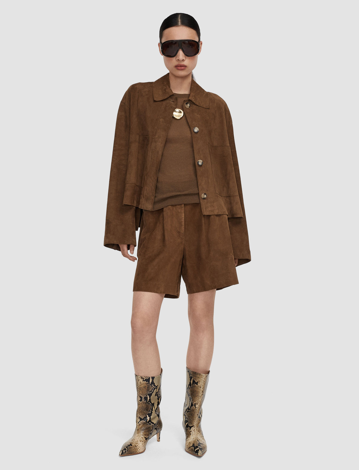 A model wearing a brown suede-like cropped jacket from Jospeh, matching brown top and shorts set. 