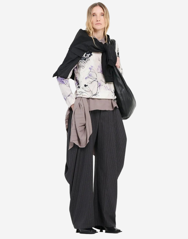 Person wearing a floral top, black scarf, and wide-leg pants on a white background