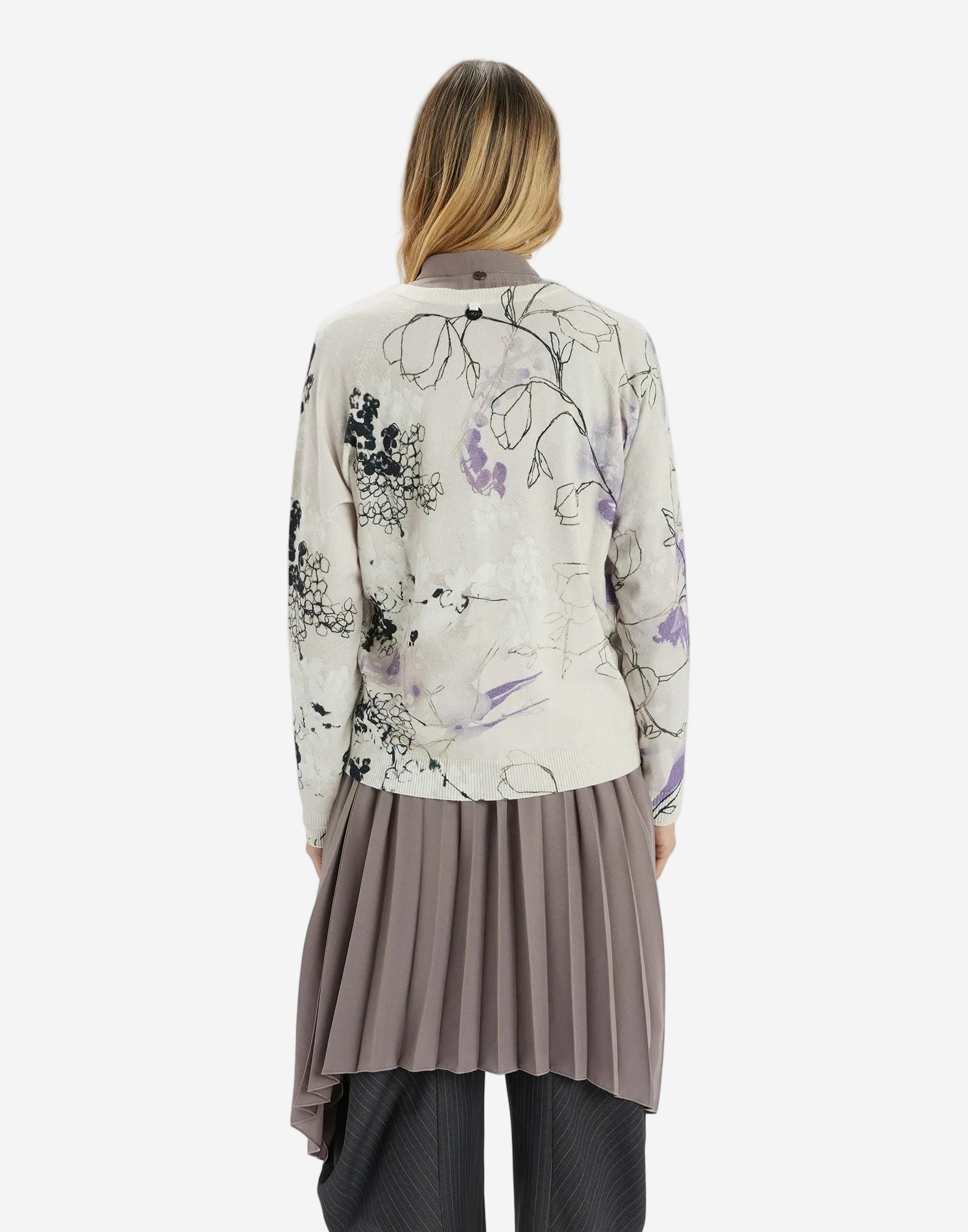 Person wearing a floral-patterned jacket and pleated skirt on a white background