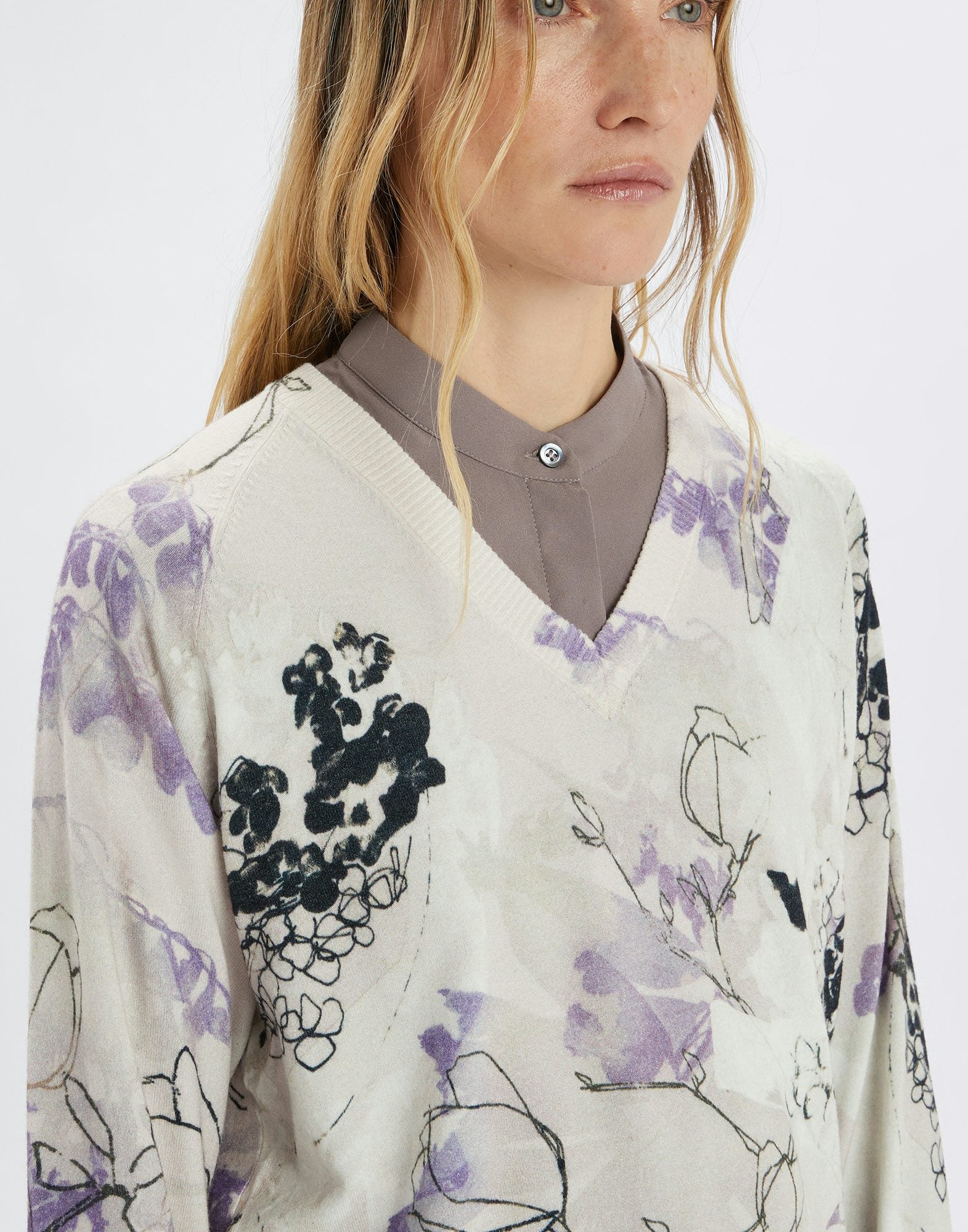 Person wearing a floral cardigan with a neutral background