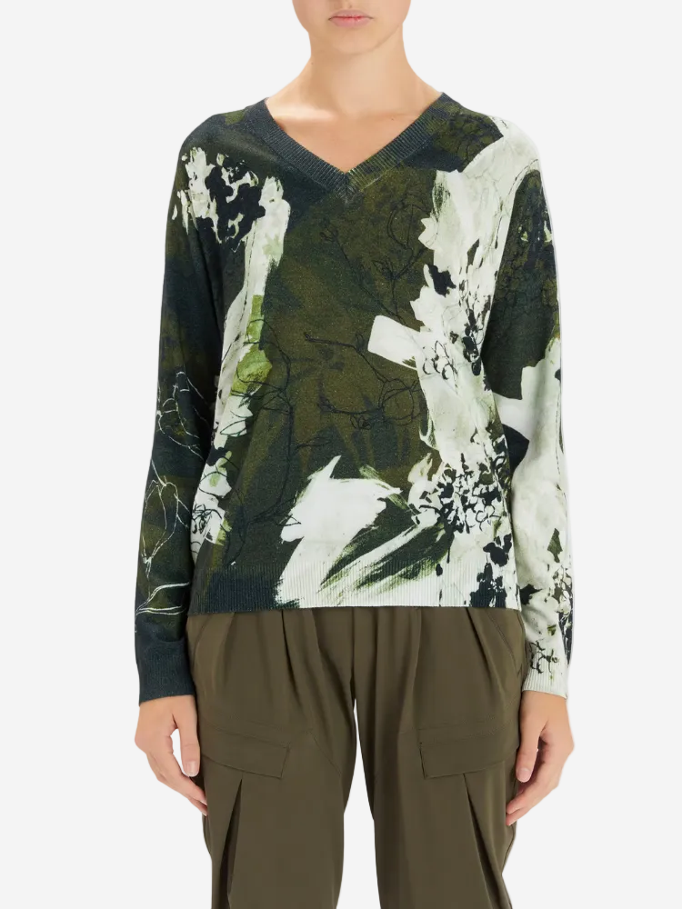 Person wearing a long-sleeve top with abstract design and olive green pants on a light gray background