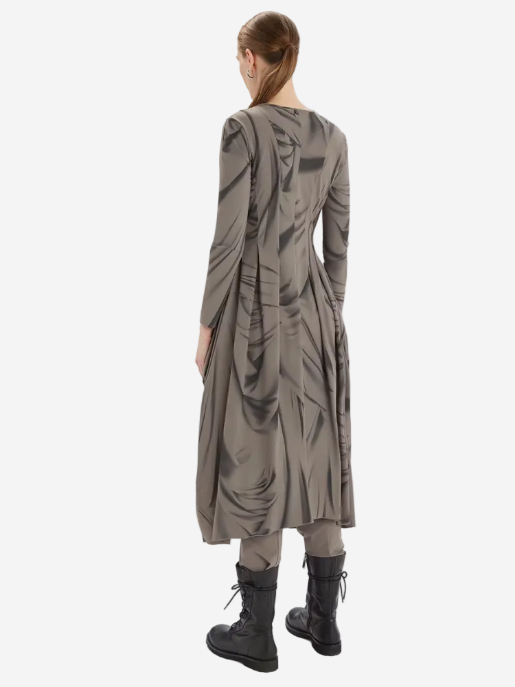 Person wearing a long, dark gray dress with geometric patterns on a white background
