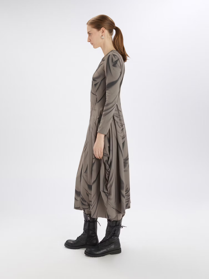 Woman wearing a long, dark gray dress with a white background
