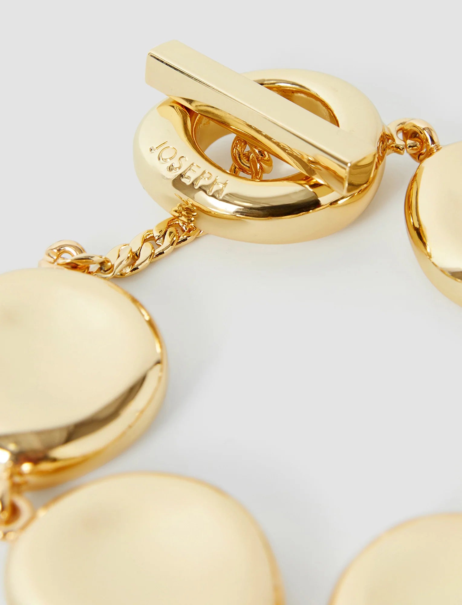 Gold bracelet with heart-shaped links on a light gray background