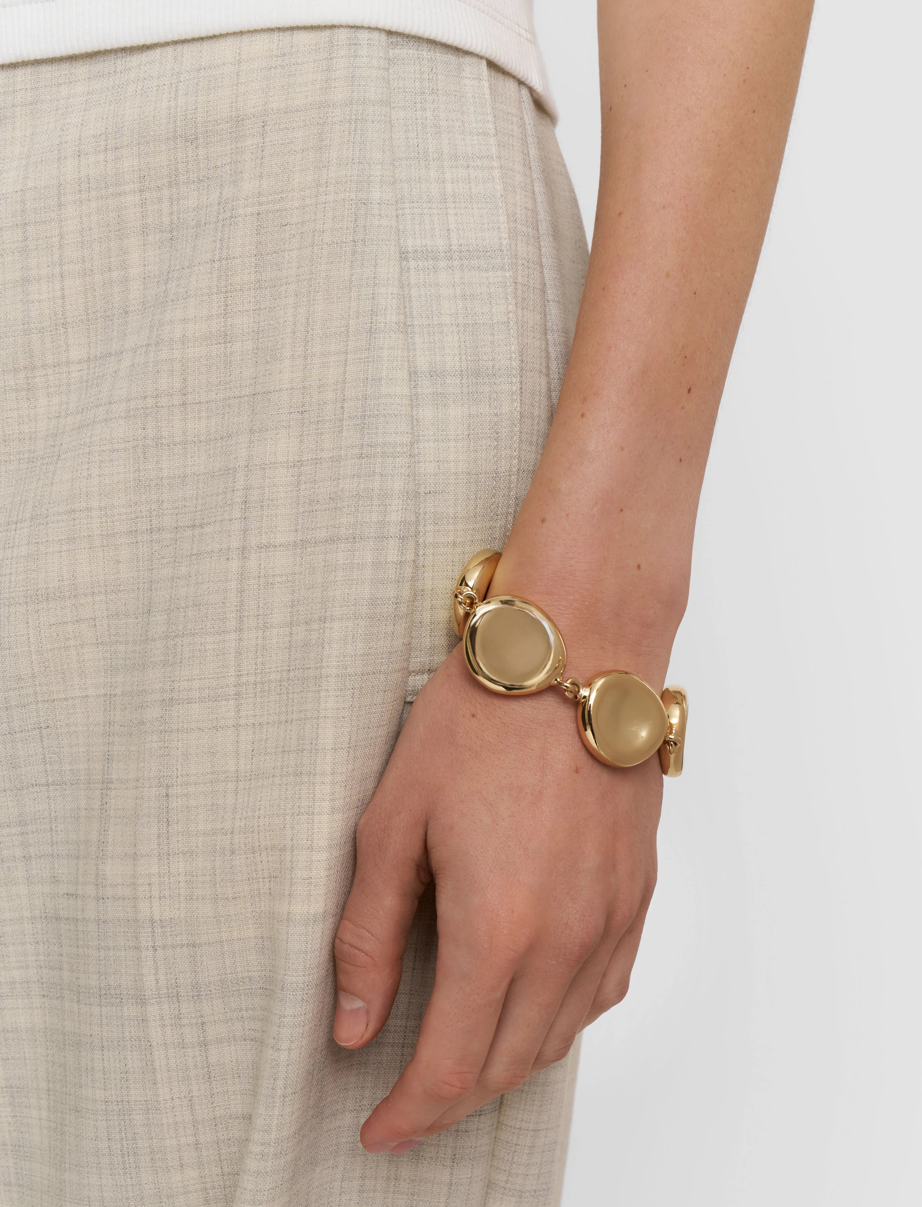 Gold bracelet on a wrist with a neutral background