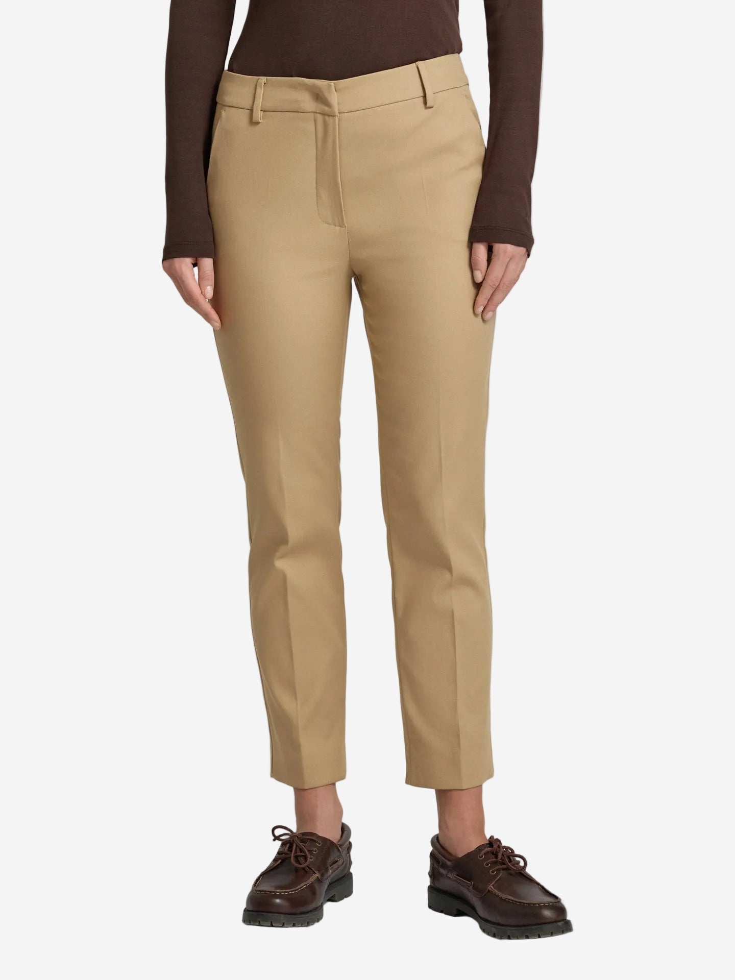 Person wearing beige pants and brown shoes on a white background