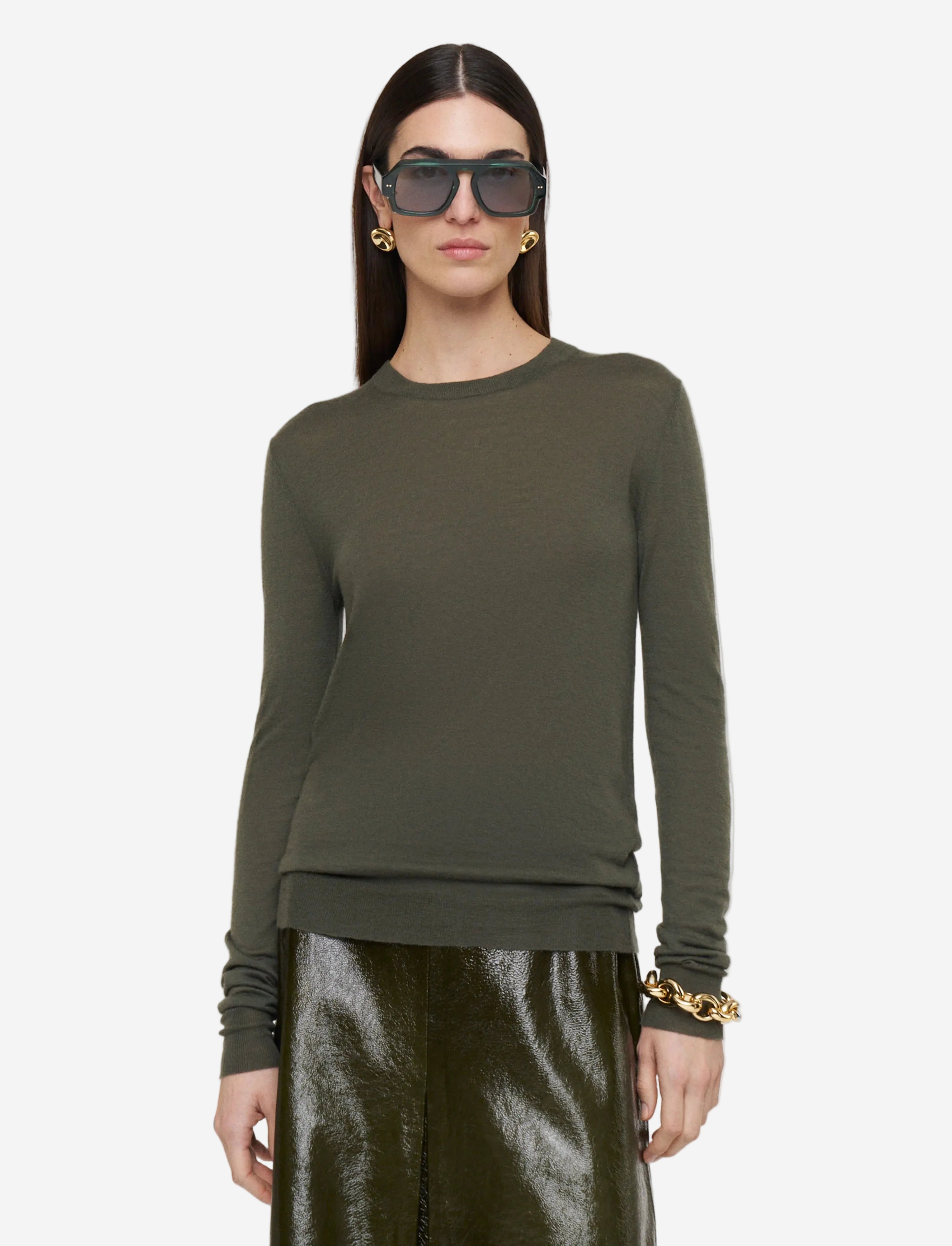Woman wearing an olive green long-sleeve top and matching pants on a light gray background