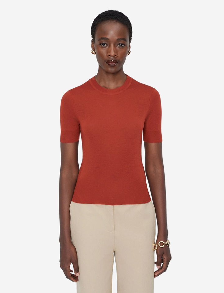 Woman wearing a red sweater and beige pants on a white background