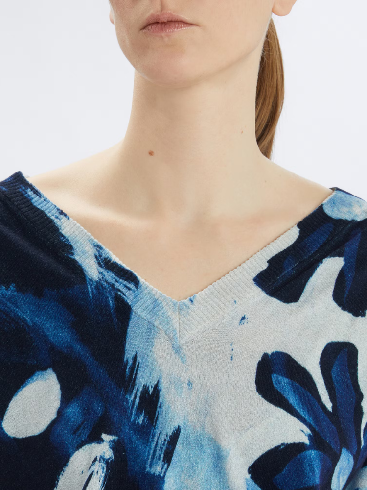 Close-up of a person wearing a blue and white patterned top with a blurred background