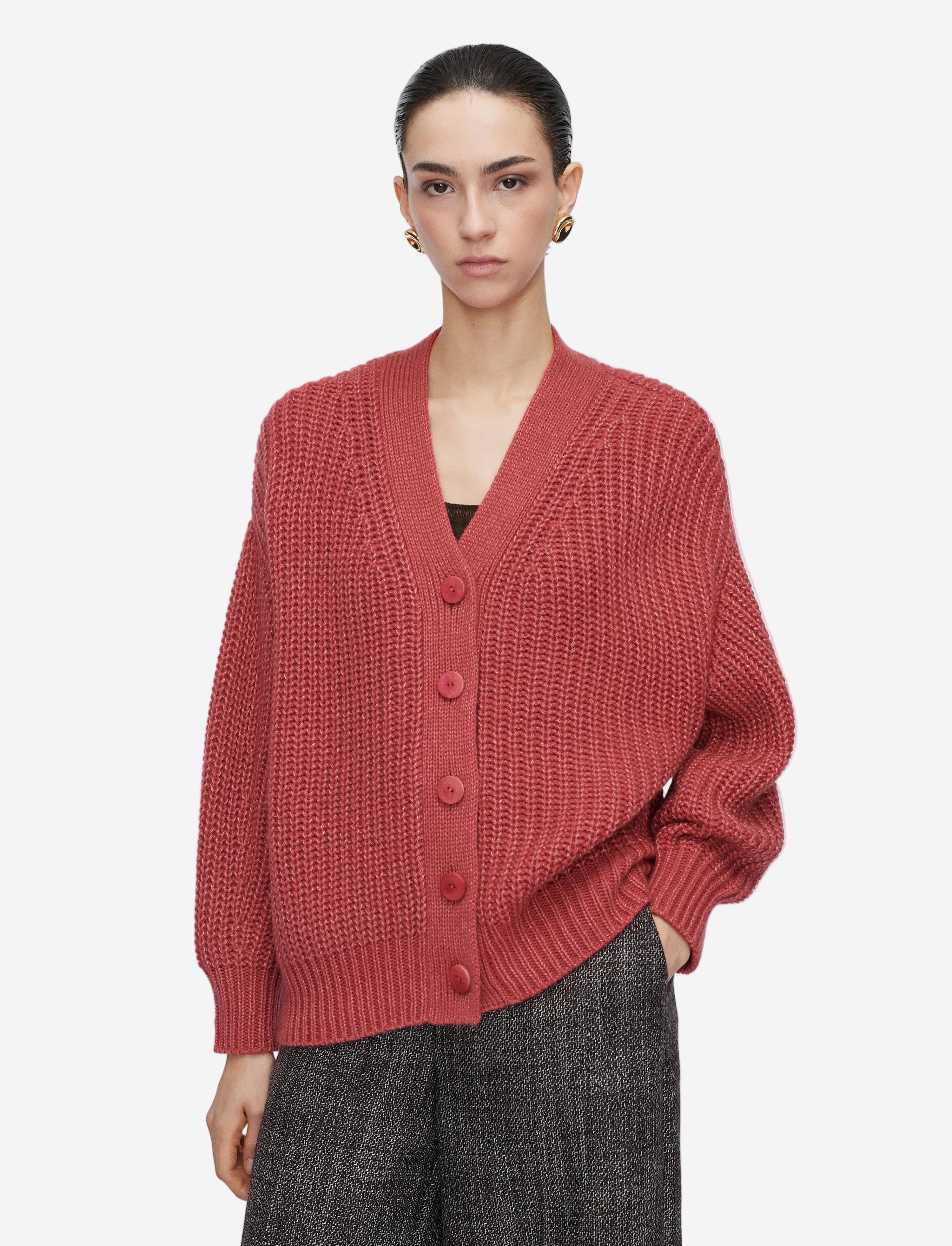 Person wearing a red knitted cardigan on a plain background