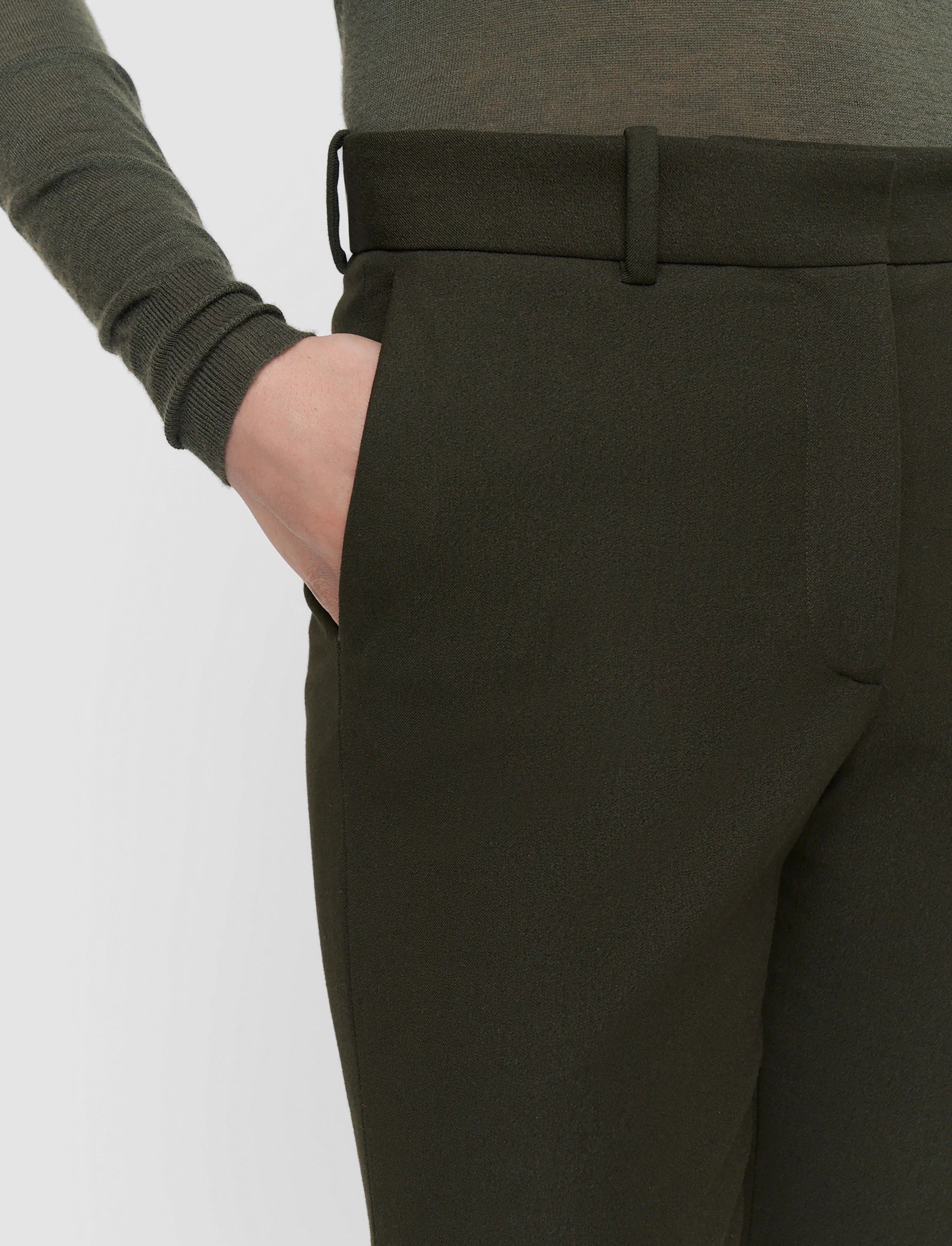 Dark green pants worn by a person on a light gray background