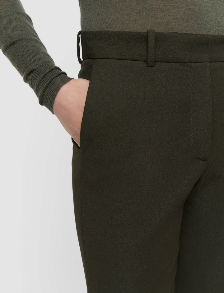 Dark green pants worn by a person on a light gray background