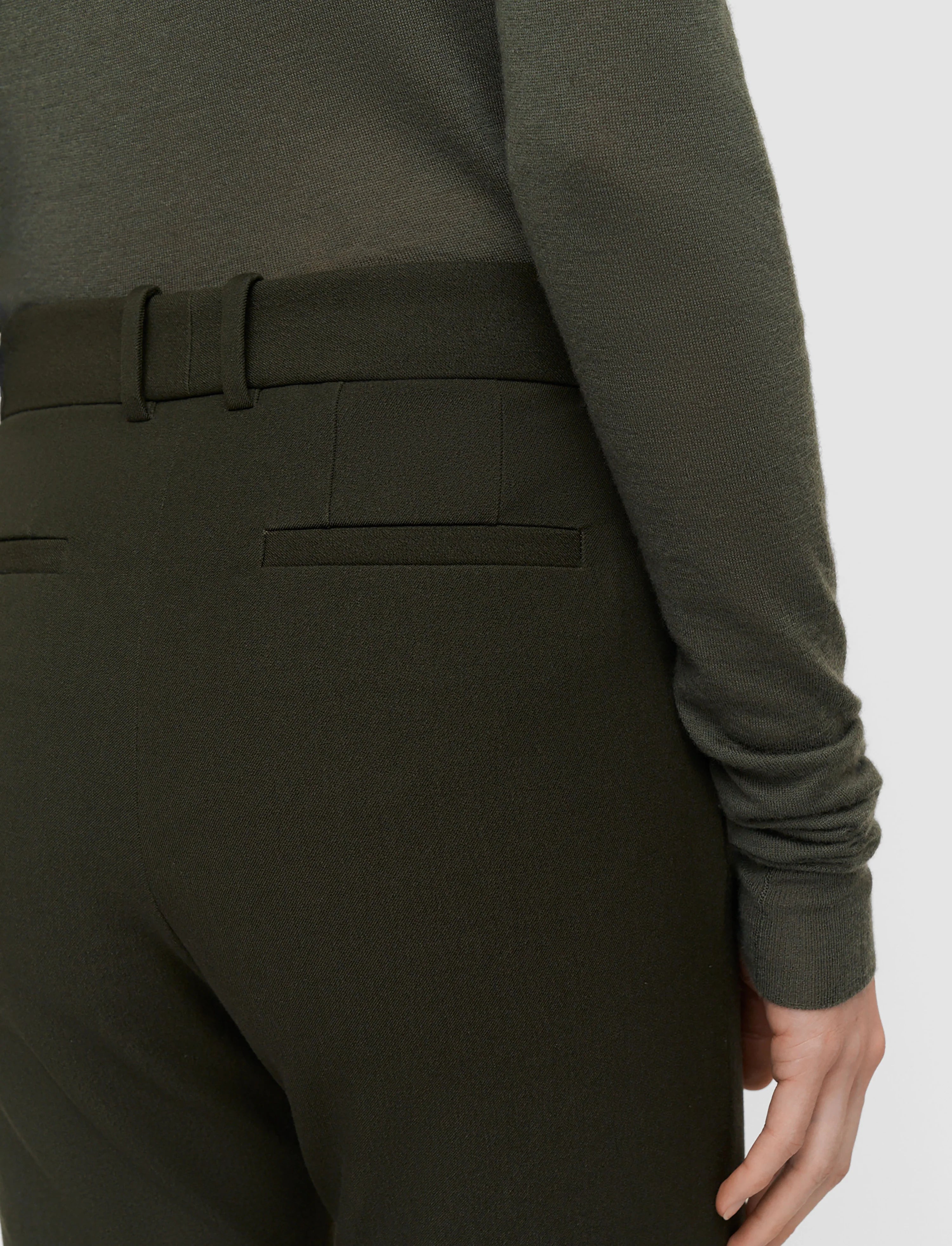Person wearing a dark green outfit with a belt on a white background