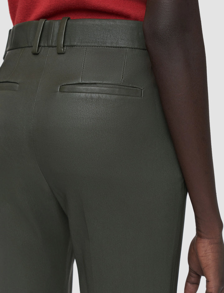 Dark green pants worn by a person on a white background