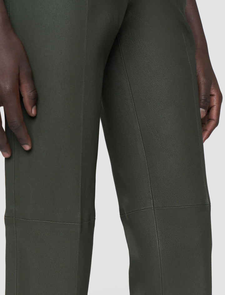 Dark green pants worn by a person on a light gray background